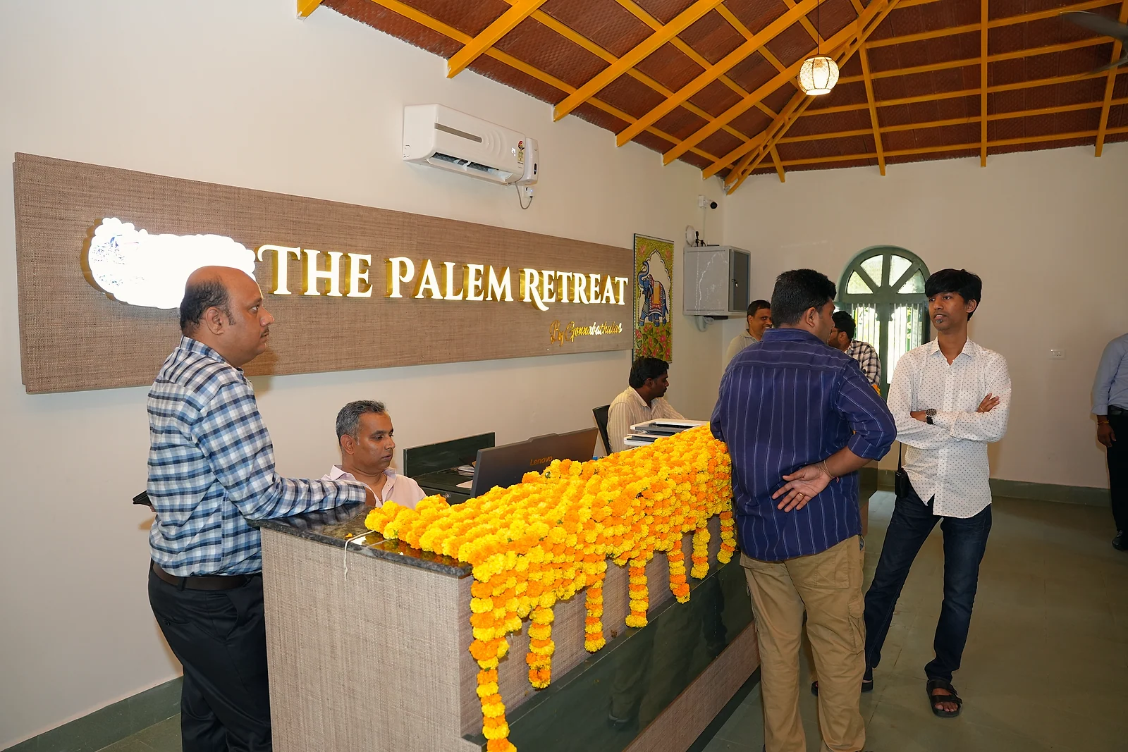 Guests at the marigold-decorated reception desk beneath The Palem Retreat sign