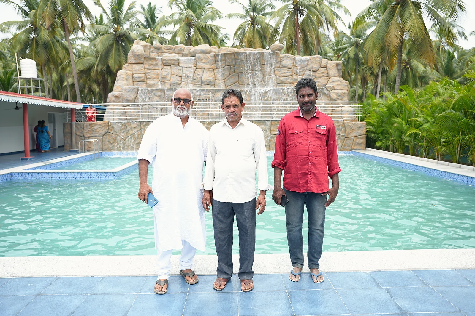 Three guests posing beside the pool and waterfall during the grand launch