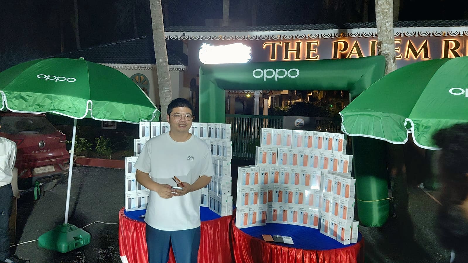 An attendee standing beside the OPPO product display and branded green umbrellas